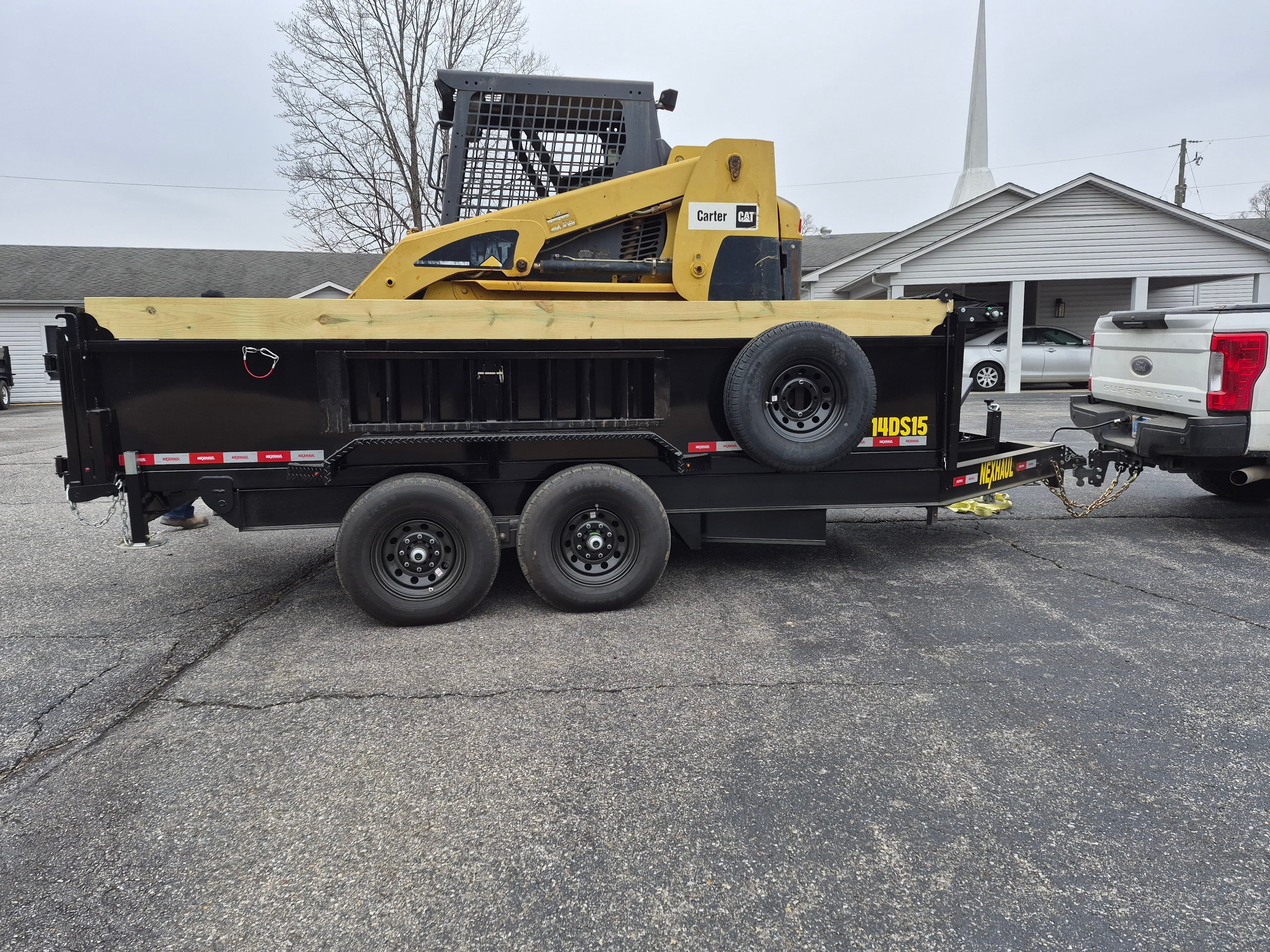 Side view of black and yellow dump trailer with dual axles showing professional construction