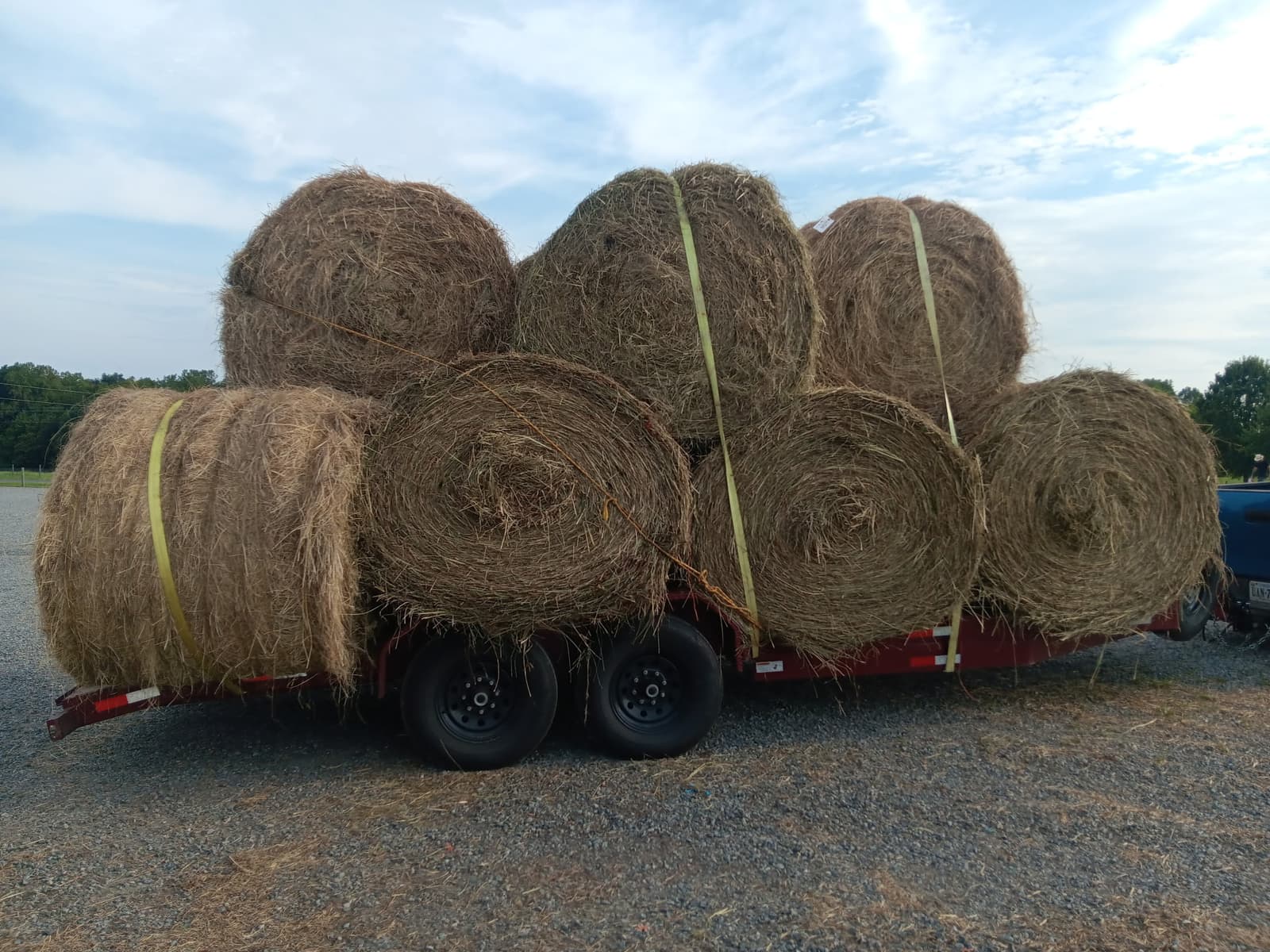 Round hay bales stacked and secured on a red J&T equipment trailer