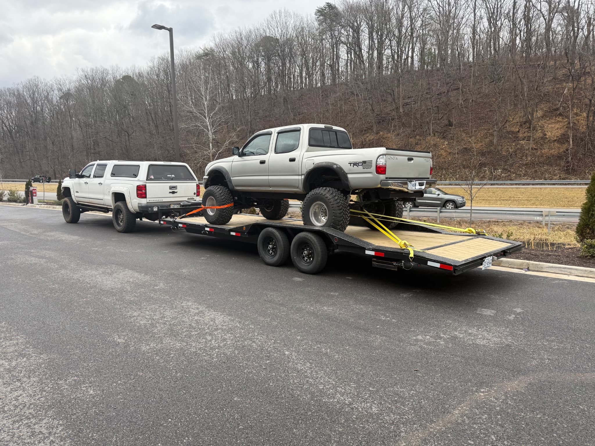 Car trailer with one vehicle towing and another vehicle positioned on the trailer deck demonstrating dual-vehicle hauling