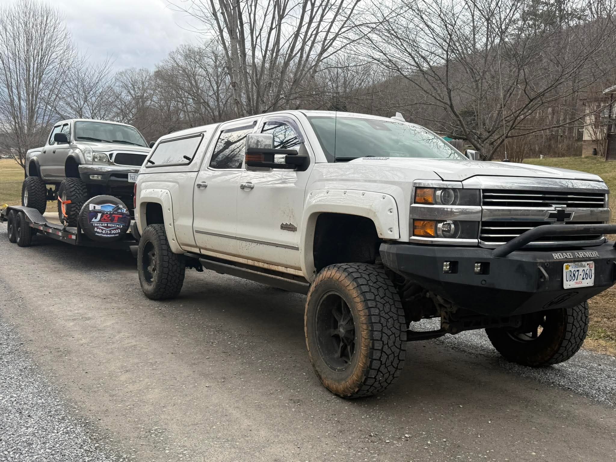 Professional car trailer rental in Bedford VA carrying two pickup trucks with yellow tie-down straps