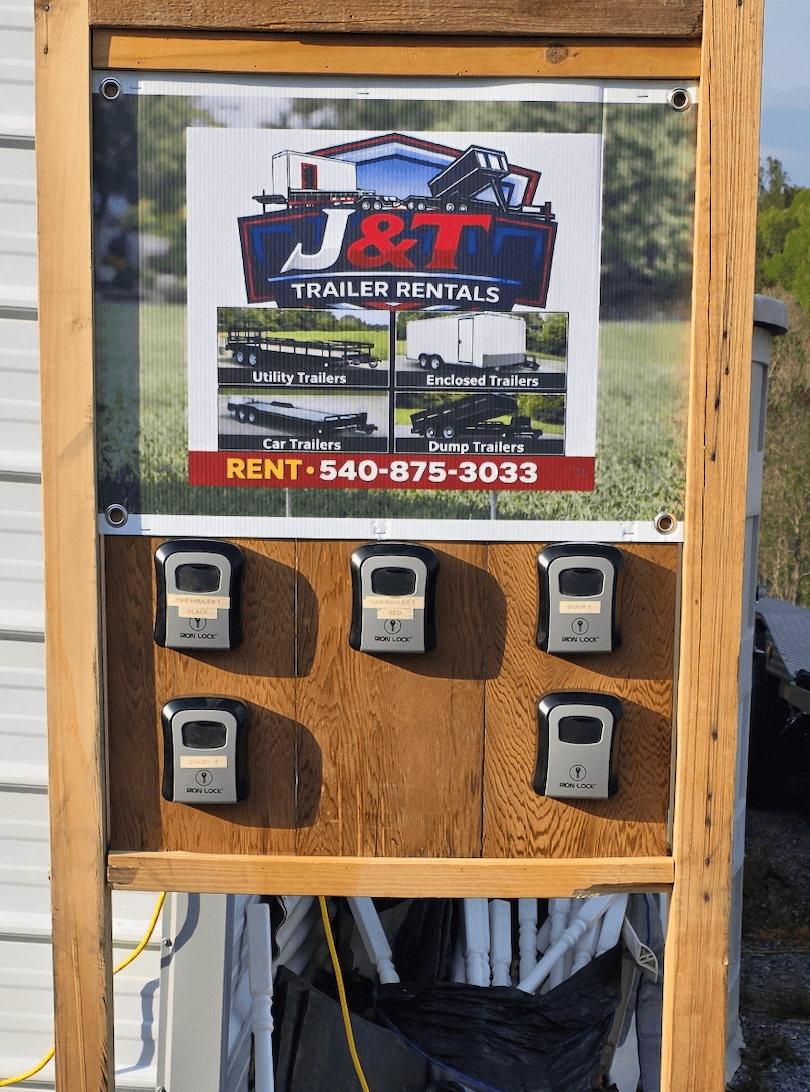 J&T Trailer Rentals self-service key lockbox station with five Iron Lock combination boxes mounted on a wood board with a J&T banner sign above